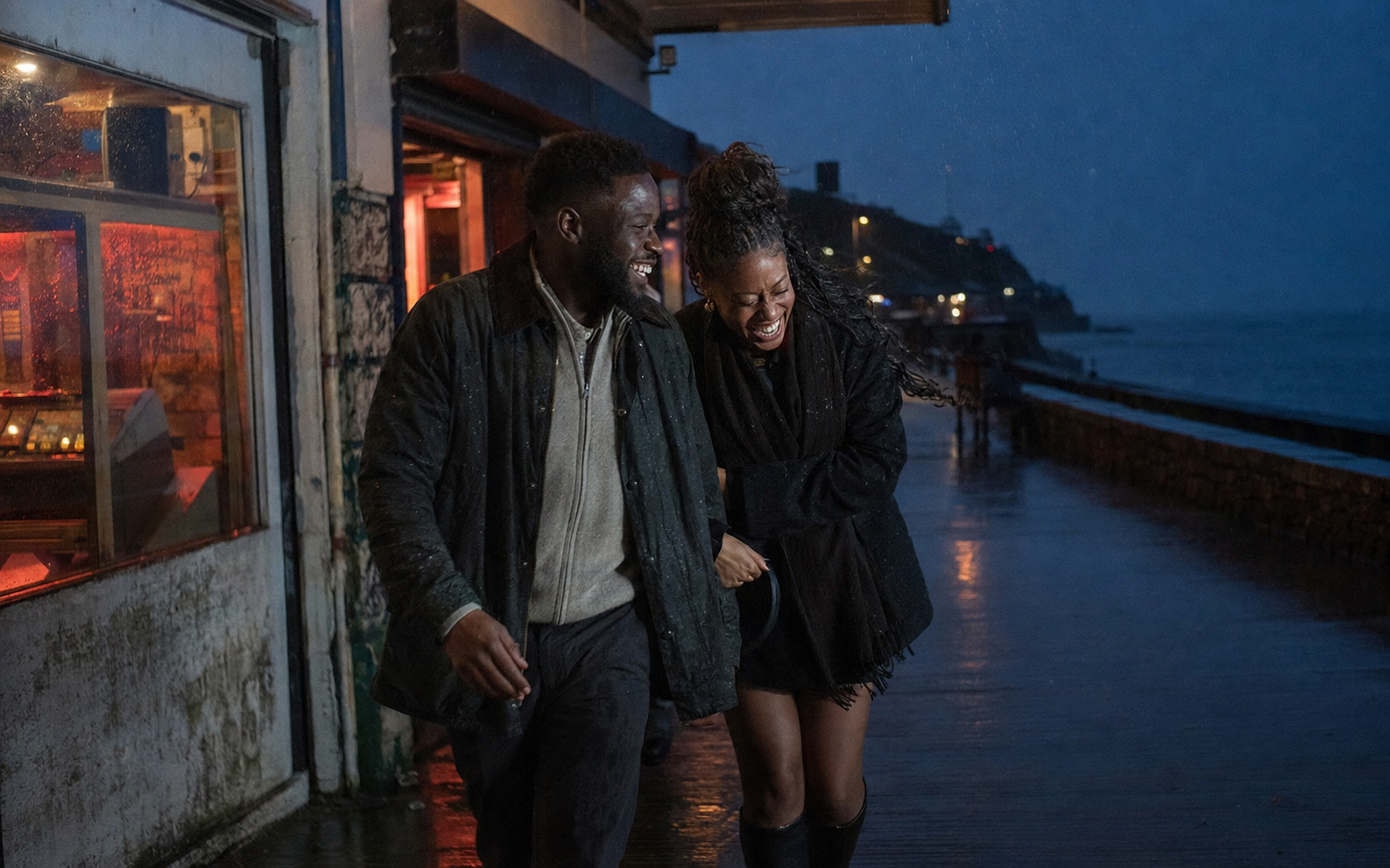 A young Black British couple laughing at the Welsh seaside
